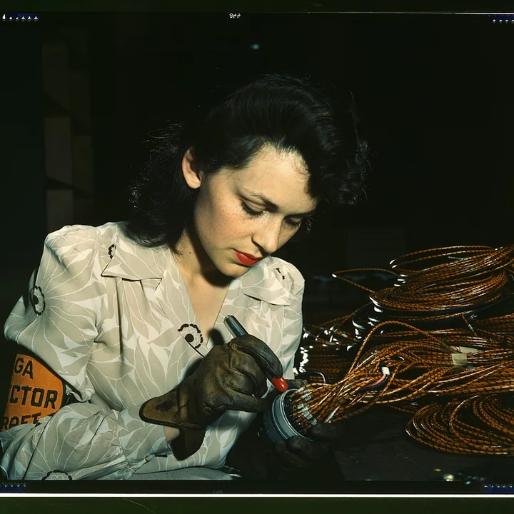 An aircraft worker carefully checks an electrical assembly by hand.