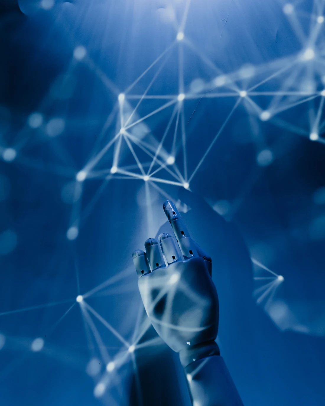 A robotic hand reaching toward a projected network of glowing nodes.